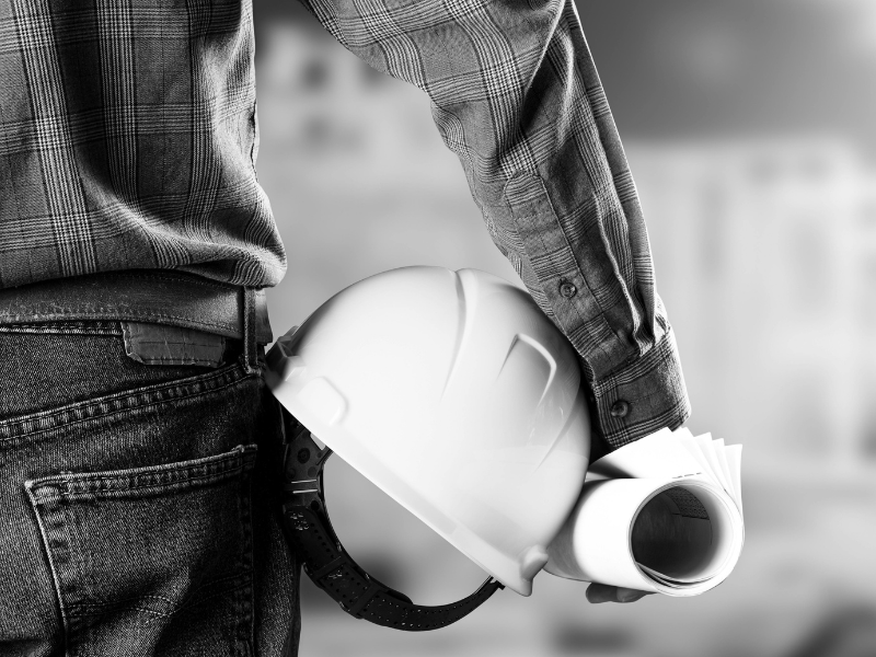 Worker holding a hard hat and rolled construction plans